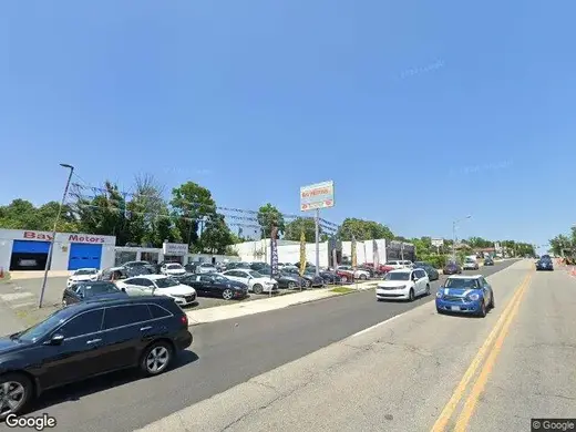 Street view of One Promise Behavioral Health, a detox center in Baltimore, surrounded by cars and businesses.
