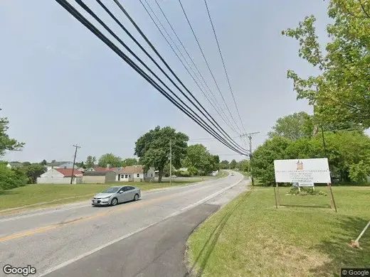 Roadside sign for Positive Generation In Christ Inc, a treatment center in Baltimore, surrounded by greenery.