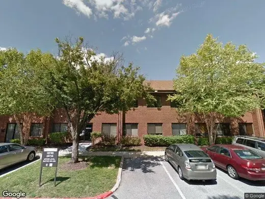Brick exterior with trees and parking lot at Arise Health Clinic, a treatment center in Baltimore.